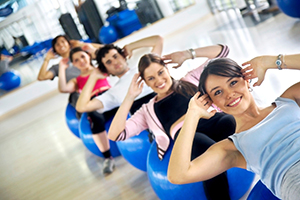 group of people at the gym smiling an doing abs exercises